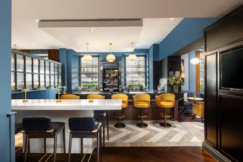 a bar in a restaurant with yellow stools at Courtyard by Marriott Edinburgh in Edinburgh