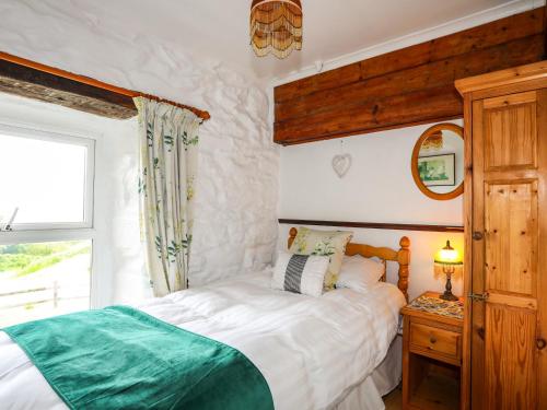 a bedroom with a white bed and a window at Hendy Cottage in Llanbedr