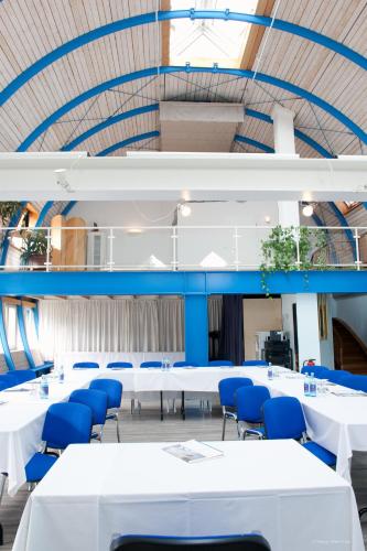 a conference room with white tables and blue chairs at Hotel Georg in Witten