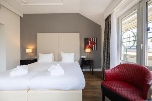 a bedroom with a white bed and a red chair at Grand Hotel Amrâth Kurhaus The Hague Scheveningen in Scheveningen