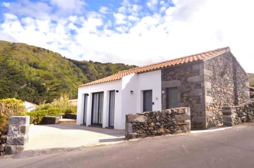 a small white building with a stone wall at Beachscape Cottage in Fajã