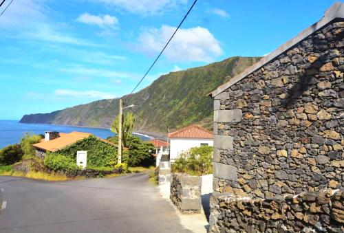 a stone building with a mountain in the background at Beachscape Cottage in Fajã