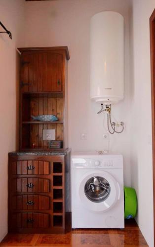 ein Waschraum mit Waschmaschine und Schrank in der Unterkunft Beachscape Cottage in Fajã
