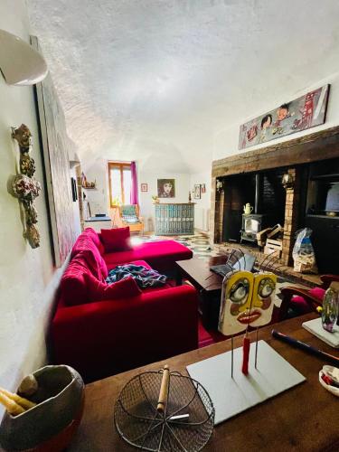 - un salon avec un canapé rouge et une cheminée dans l'établissement L’insolite, à Meyrannes