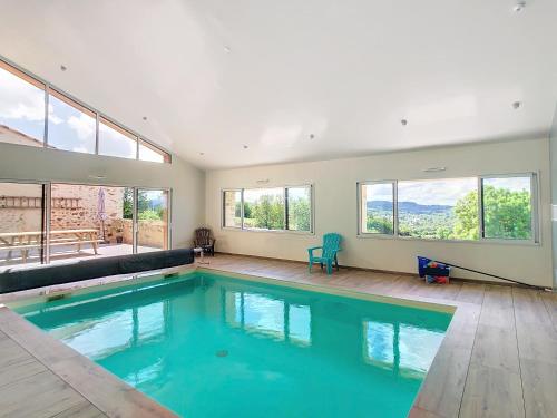 - une grande piscine dans une maison dotée de fenêtres dans l'établissement Au Vent des Collines, aux Épesses