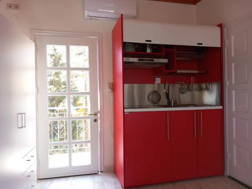 a kitchen with red cabinets and a red door at Studio Kastro I in Mirina