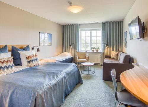 une chambre d'hôtel avec un lit, un canapé et une table dans l'établissement Color Hotel Skagen, à Skagen