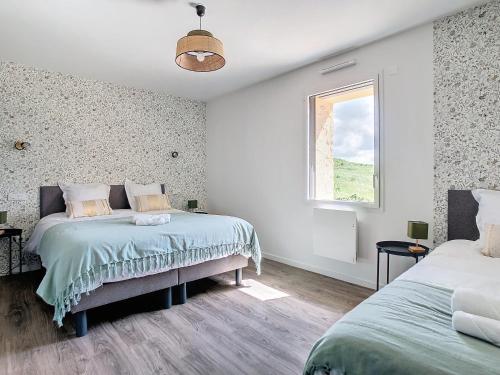 een witte slaapkamer met twee bedden en een raam bij Au Vent des Collines in Les Épesses