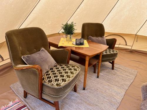 two chairs and a wooden table and a table and chairs at Hommen Gård Glamping in Risør