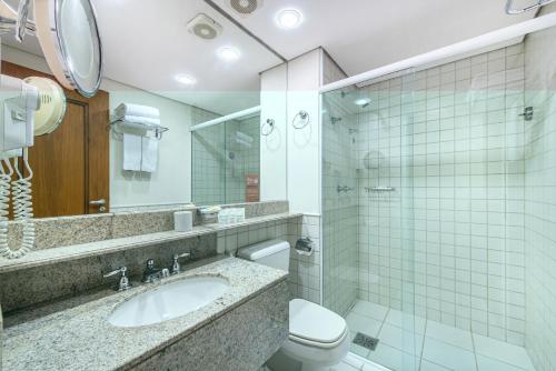 a bathroom with a sink and a toilet and a mirror at Hotel Cassino Tower Campinas Cambuí in Campinas