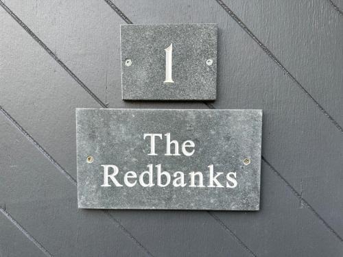 a sign that reads the redbacks hanging on a wall at Redbanks Apartment in Ambleside