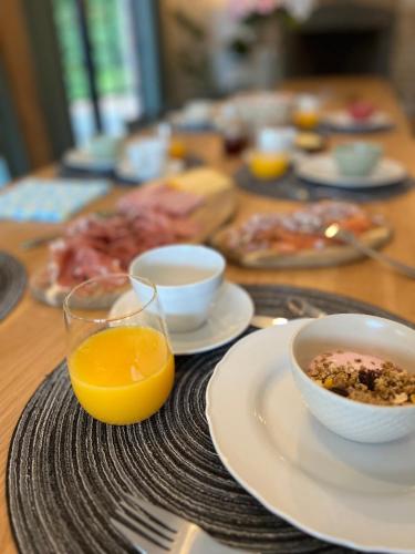 a table with plates of food and a bowl of orange juice at Vakantiewoning Domein Hooverbosch in Zonnebeke
