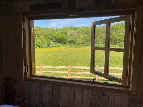 a window with a view of a field and a fence at Whittlewood Shepherd's Hut in Silverstone, Cosy, Rural, Views in Silverstone