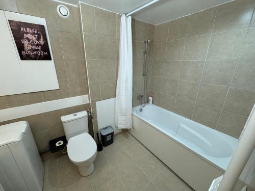 La salle de bains est pourvue d'une baignoire blanche, de toilettes et d'un lavabo. dans l'établissement Eclectic apartment in Paris near Montmartre, à Paris