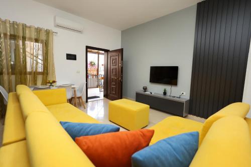 a living room with yellow and blue couches and a television at Berat Central Apartment in Berat