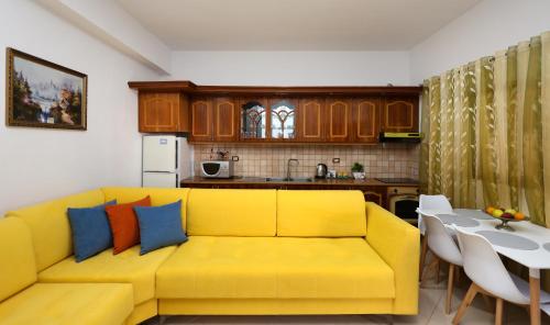 a living room with a yellow couch and a kitchen at Berat Central Apartment in Berat