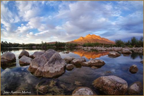 a mountain in the middle of a lake with rocks at Lodge Hara Oasis in Agdz