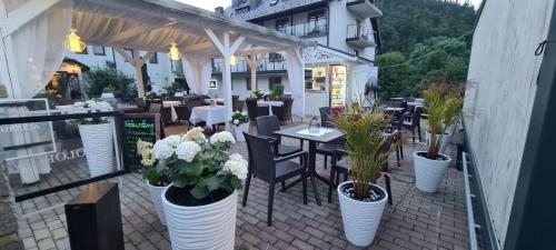 a patio with tables and plants in white vases at Hotel Kolorowa in Karpacz