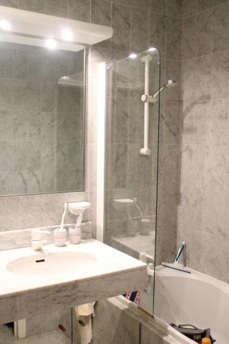 une salle de bain avec un lavabo et une douche en verre dans l'établissement Victoria Palace, à Menton