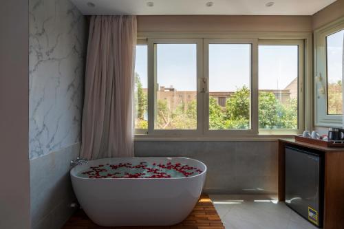 a bathroom with a large white tub in front of windows at Dream Inn in Cairo