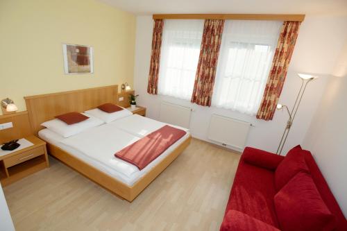 a bedroom with a bed and a red couch at Urbarialhof in Illmitz