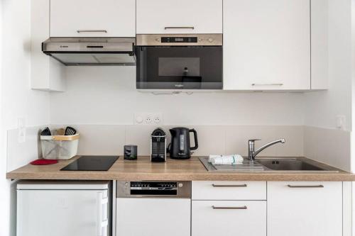 une cuisine blanche avec un évier et un micro-ondes dans l'établissement Sunset, à Saint-Malo