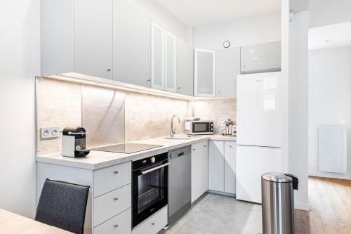 une cuisine blanche avec des armoires et des appareils blancs dans l'établissement GuestReady - Confort Moderne près des Invalides, à Paris