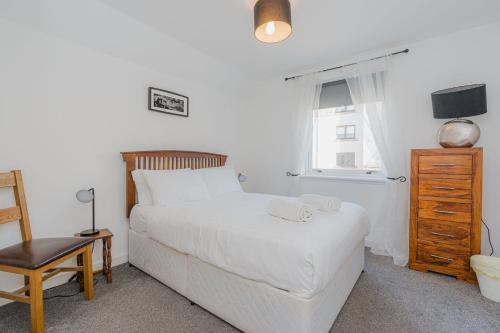een slaapkamer met een wit bed, een stoel en een raam bij GuestReady - Restful stay near Edinburgh Castle in Edinburgh