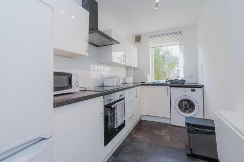 een witte keuken met een wasmachine en droger bij GuestReady - Restful stay near Edinburgh Castle in Edinburgh