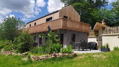 a home with a wooden roof and a patio at Gîte Le Charme d'Argent in Charmois-devant-Bruyères