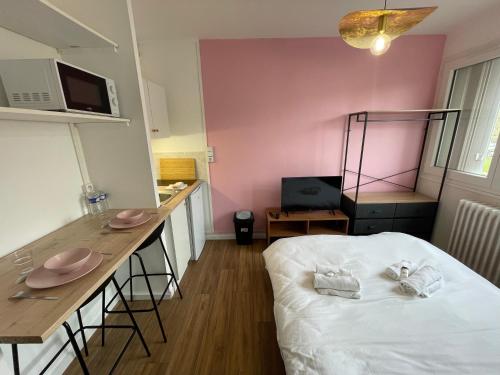 Cette chambre comprend un lit, une table et un comptoir. dans l'établissement Roza, Studio proche centre ville, à Caen
