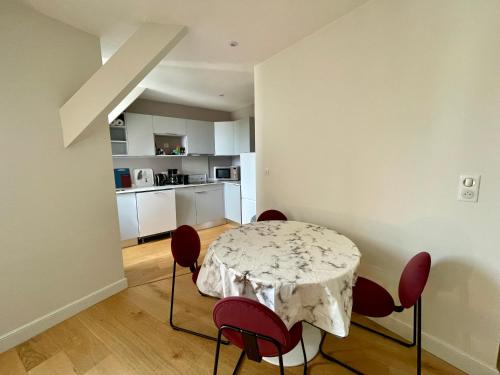 une salle à manger avec une table et des chaises rouges dans l'établissement Charmant Appartement au Coeur de l'Avenue Lajarige, à La Baule