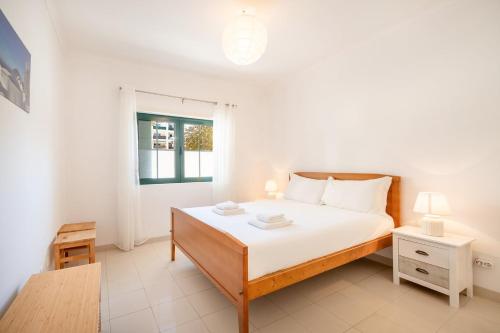 een witte slaapkamer met een bed en een raam bij GuestReady - Relaxation near Carcavelos Beach in Carcavelos