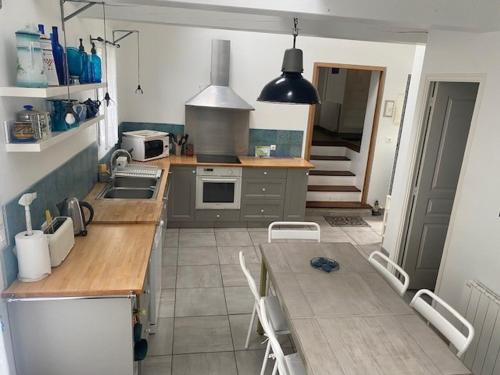 une cuisine avec un évier et une table avec des chaises dans l'établissement Charmante maison proche plage à Locmaria, 4 pers, jardin, cheminée, équipements complets - FR-1-418-97, à Locmaria