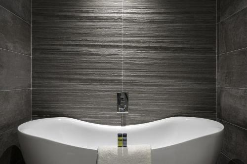 uma banheira na casa de banho com uma parede cinzenta em Bayview Hotel em Ballycotton