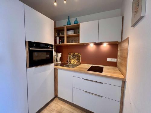 une cuisine avec des armoires blanches et un comptoir en bois dans l'établissement Quiberon - 2 pièces rénové avec wifi, parking et balcon - Animaux admis - FR-1-478-88, à Quiberon