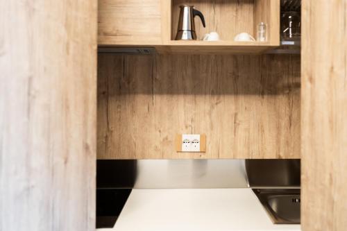 a kitchen with wooden cabinets and a stove top oven at M-APPHOTEL in Benna
