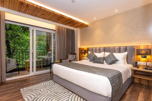 a bedroom with a large bed and a balcony at The Belvedere Himalayan Retreat, Mcleodganj, Dharamshala - By Leisure Hotels in McLeod Ganj