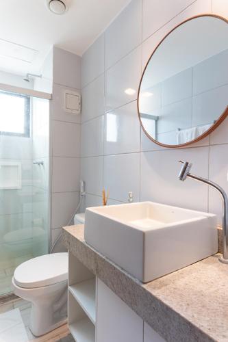a white bathroom with a sink and a mirror at La Fleur Polinésia in Porto De Galinhas