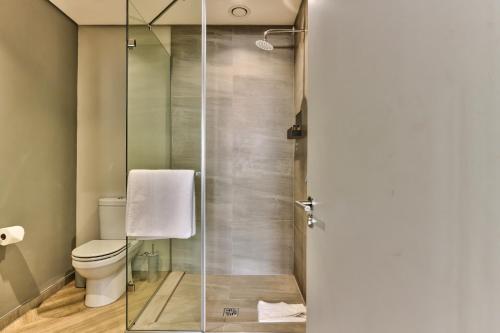 a bathroom with a glass shower with a toilet at WINK Aparthotel One Thibault in Cape Town