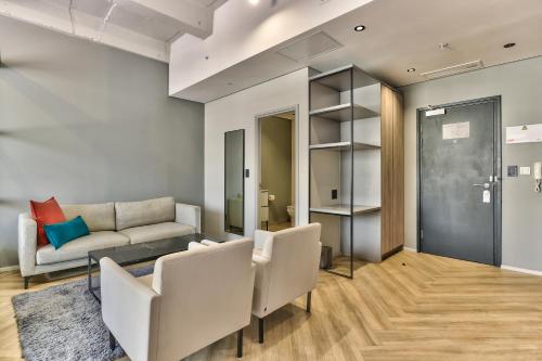 a living room with white chairs and a couch at WINK Aparthotel One Thibault in Cape Town
