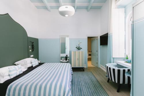 a bedroom with a bed with a striped blanket and a desk at Bela Vista Hotel & Spa - Relais & Chateaux in Portimão
