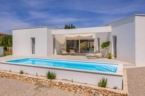 a villa with a swimming pool in front of a house at Villa MENTA IV in Linardići