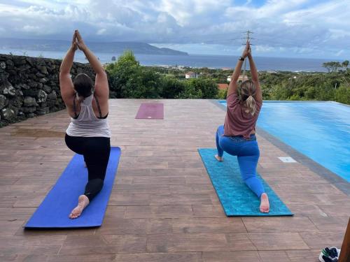 two women doing yoga by a swimming pool at Adega da Quinta - Casa da Gigi in Madalena