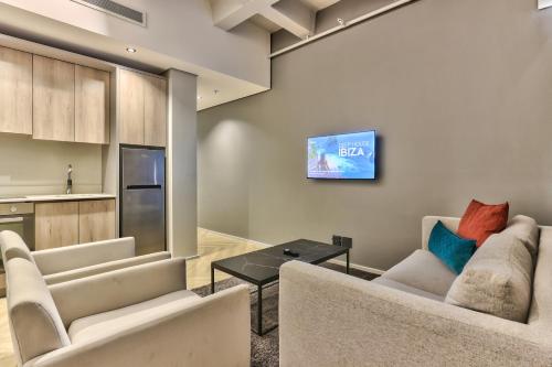 a living room with two couches and a tv at WINK Aparthotel One Thibault in Cape Town