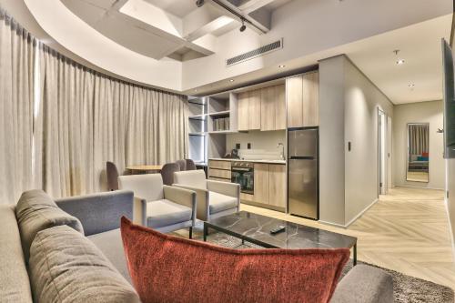 a living room with a couch and chairs and a kitchen at WINK Aparthotel One Thibault in Cape Town