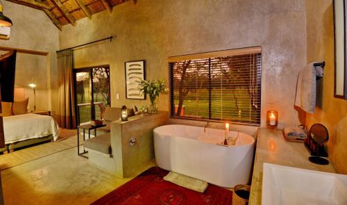uma casa de banho com uma banheira e um quarto com uma cama em Ngala Lodge em Klipdrift