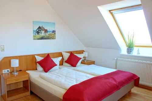 a bedroom with a bed with red pillows and a window at Baltic Kölln Appartement in Heiligenhafen