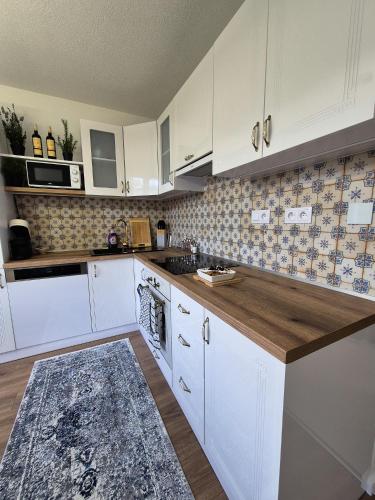 a kitchen with white cabinets and a wooden counter top at Apartmán Lesa Brezno in Brezno