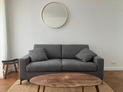 a living room with a grey couch and a mirror at Maison le Bac Apartments in Paris